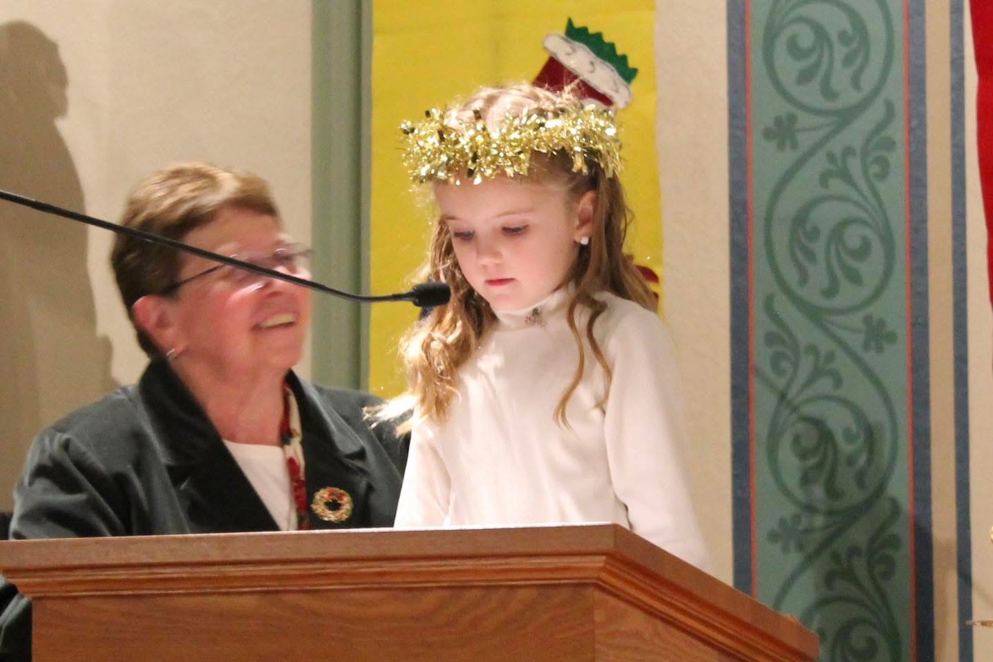 Photo of a kindergarten student reading at Lessons & Carols.